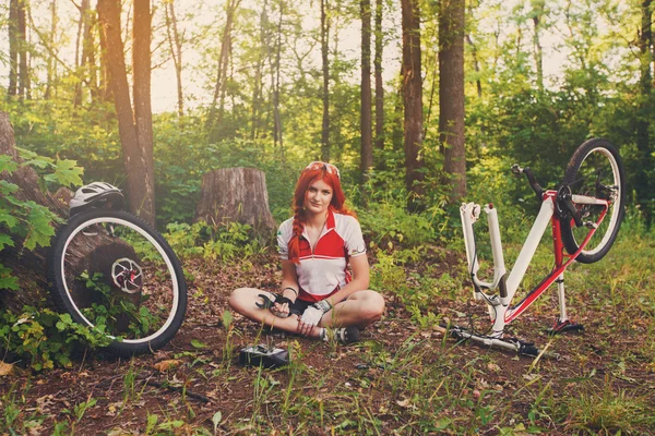 Joven ciclista deportista reparando su bicicleta mtb en el bosque — Foto de Stock