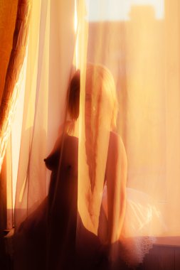 Pencere perde arkasında duran çıplak kadın 