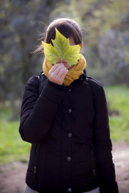 Bir yaprak ile yüzünü kaplayan kadın