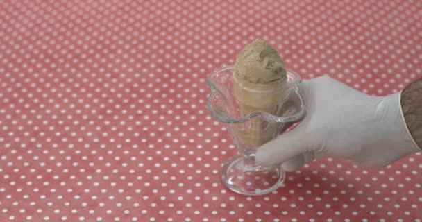 ruka v rukavici dávat skleněnou misku s karamelovou zmrzlinou kornout na stůl a brát ji zpět