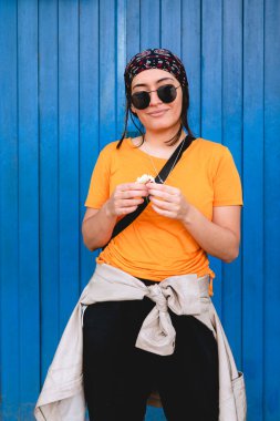 Mujer con flor en la mano rionera y campera atada en atardecer primaveral lentes de sol frante