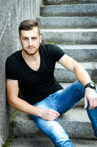 Hombre guapo sentado contra la pared —  Fotos de Stock