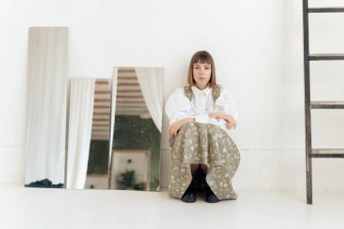 Stüdyoda poz veren eski moda elbiseli muhteşem genç kadın.