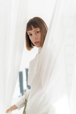 Pencerenin yanında poz veren eski moda elbiseli genç kız. 