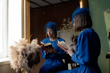 Eski moda kıyafet kitabı okuyan genç bir kız.