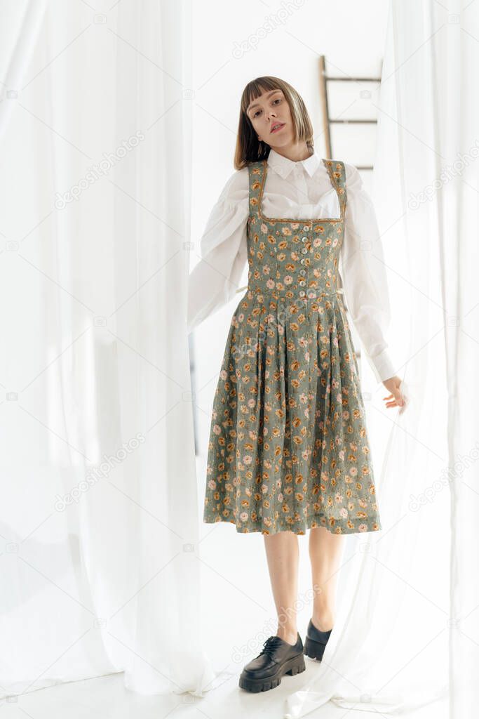 young girl in old fashione clothes posing near the window 
