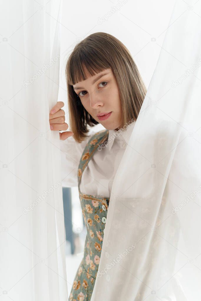 young girl in old fashione clothes posing near the window 