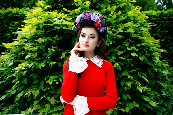 Woman in red dress with a flower wreath — Stock Photo, Image