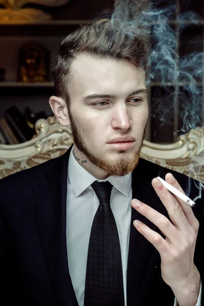 Man sitting in vintage chair with a cigarette — Stock Photo, Image