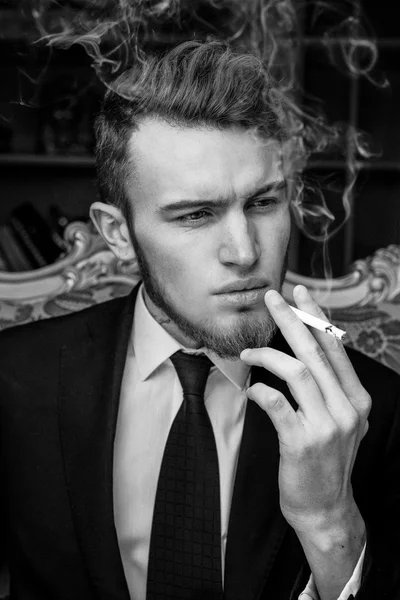 Uomo seduto su una sedia vintage con una sigaretta — Foto Stock