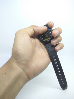 Sol el beyaz arka planda siyah bir saat tutuyor.