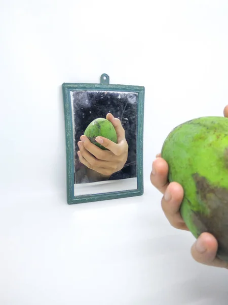 Eine Hand Und Eine Halb Verfaulte Mango Vor Einem Spiegel — Stockfoto