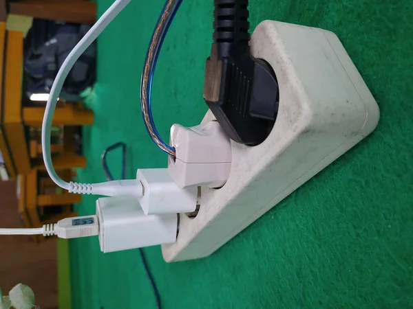 Many plugs and adapters plugged into electric power strip