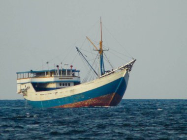 Geleneksel tekne, yağmur sisi ve mavi deniz arka planıyla