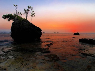 Batı kıyısında gün batımından sonraki atmosfer büyük mercan süslemeleriyle dolu.