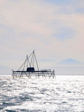 Deniz arka planı, denizin üstünde betel fındık sırıkları olan bir pangung evi.
