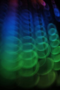 Arkaplanda bulanık fotograf altı, siyah üzerinde kıvrımlı renkli yuvarlak ışık deseni 