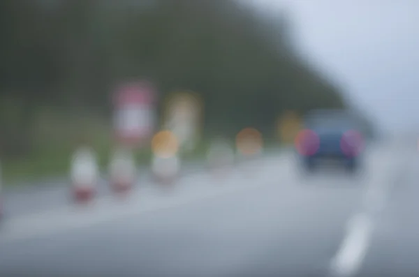Abstrato carro embaçado estrada perigosa dirigindo no dia chuvoso molhado e nebuloso. Condições de chuva e nevoeiro na auto-estrada. Desfoque de movimento visualiza a velocidade e dinâmica . — Fotografia de Stock