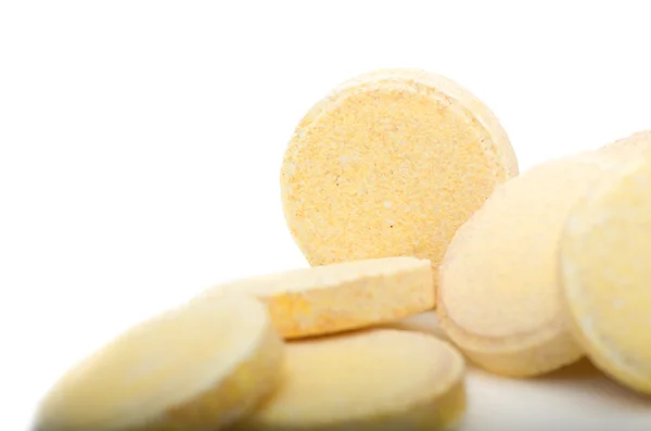 Sok kis sárga tabletták, vitaminok csoportja halom. Fehér alapon sárga tabletta — Stock Fotó