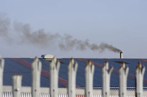 -古い塀の一部クローズ アップ。工場の作業は、青い屋根と喫煙煙突. ロイヤリティフリーのストック写真