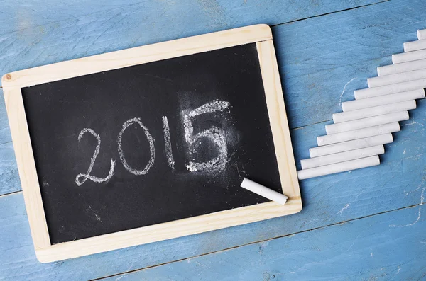 2015 written on a small blackboard with a wooden frame placed on blue wooden background. — Stock Photo, Image