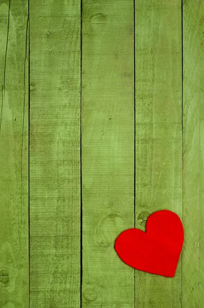 Coração vermelho feito de feltro no fundo de madeira verde . — Fotografia de Stock