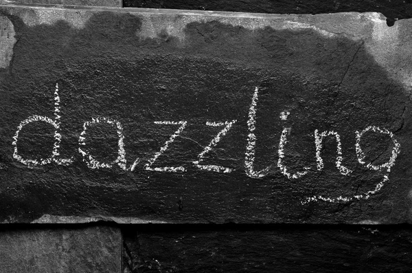 Het woord Dazzling geschreven met krijt op zwarte steen. — Stockfoto
