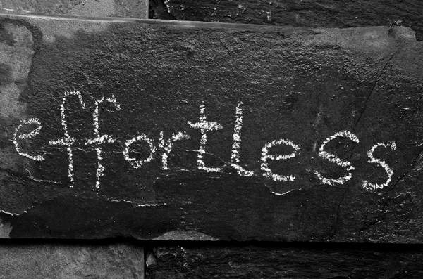 The word EFFORTLESS written with chalk on black stone. — Stock Photo, Image