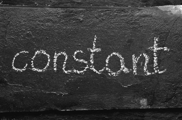 The word CONSTANT written with chalk on black stone. — Stock Photo, Image