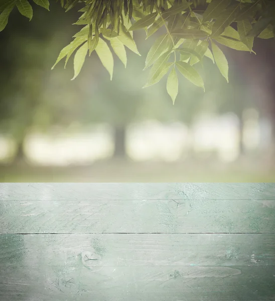 Perspectiva vazia madeira verde sobre árvores borradas com fundo bokeh, para montagem de exibição de produto — Fotografia de Stock