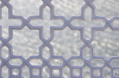 Metalik dekoratif çit. Üzerinde haç şekli korkuluk yakın çekim. Su zemin üzerine koyu gri renk.