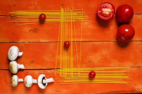 Uncooked spaghetti, cherry tomato, mushrooms on wooden background. — Stock Image Uncooked spaghetti, cherry tomato, mushrooms on wooden background. Stock Picture