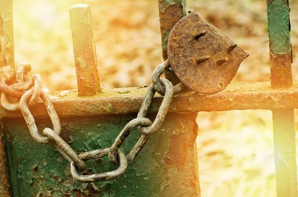 Old rusty broken lock on a green gate. Sunny day. — Stock Photo, Image