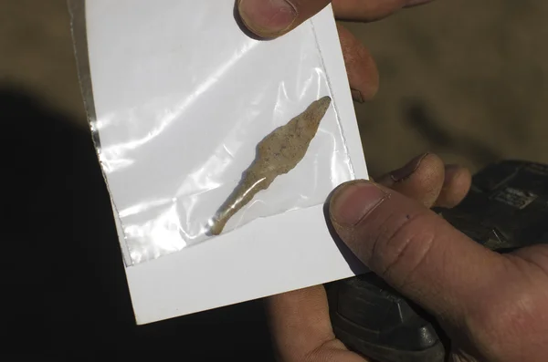 Teutonic, historical, old arrowhead in a paper bag on archaeological background. Metal detecting. — Stock Photo, Image