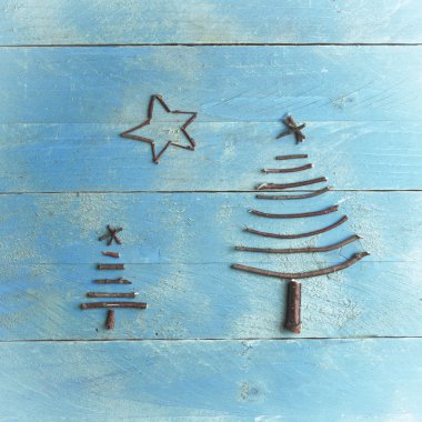 İki Noel ağaçları ve kuru sopa ahşap, mavi zemin üzerine yapılan yıldız. Noel ağacı süsleme, el sanatları.
