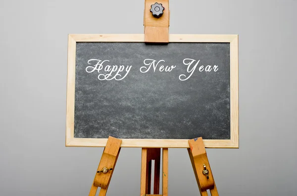 Frohes neues Jahr auf schwarzer Tafel geschrieben, Staffelei bemalt. — Stockfoto