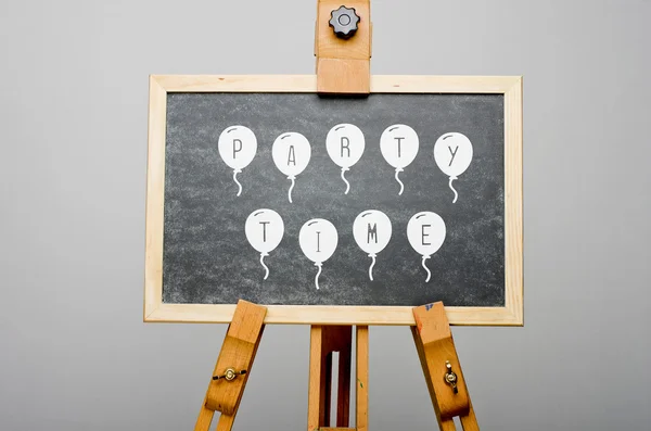 Tijd van de partij geschreven op ballonnen op zwarte schoolbord, ezel schilderij. — Stockfoto