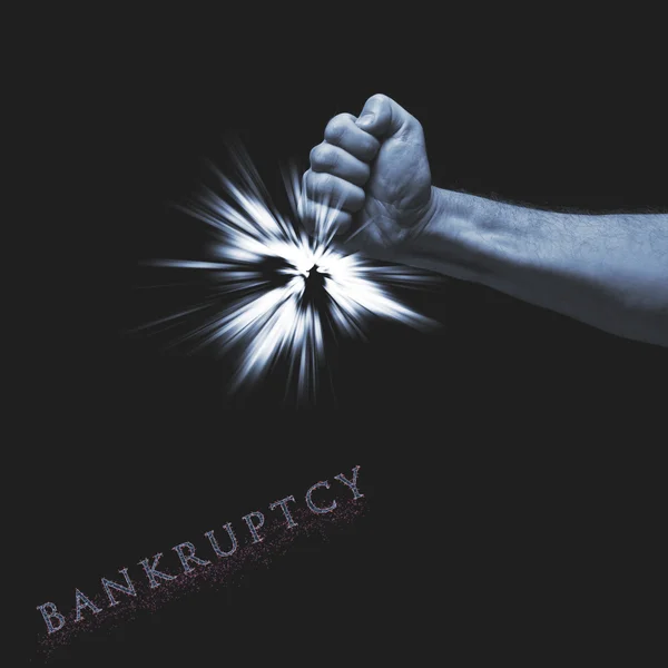Word bankruptcy written on black background. Human fist  with light under hand. — Stock Photo, Image
