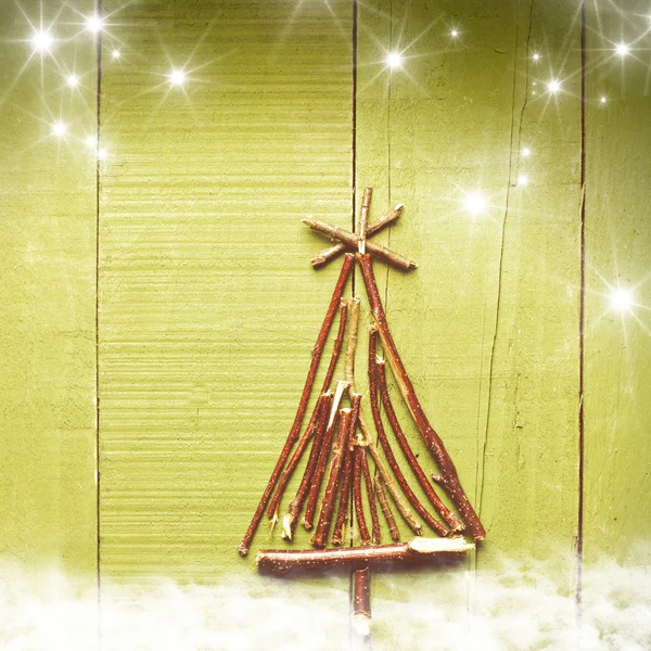 Kerstboom gemaakt van droge stokken op houten, groen, besneeuwde lichte achtergrond. — Stockfoto