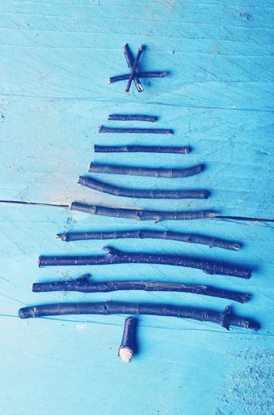 Simple árbol de Navidad arreglado a partir de palos de madera, madera a la deriva sobre fondo azul invierno de madera . — Foto de Stock