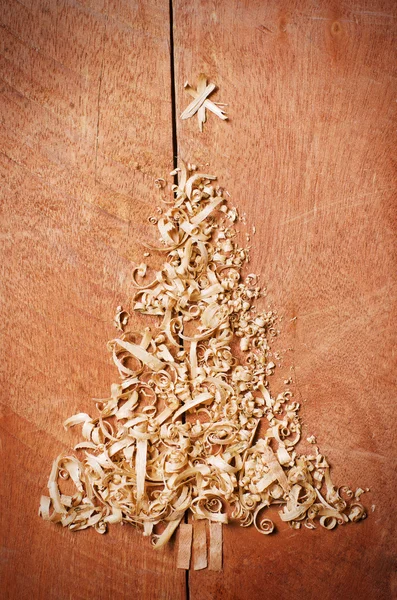 Jednoduchá vánoční strom uspořádány od piliny, dřevěné štěpky na dřevěné pozadí. — Stock fotografie