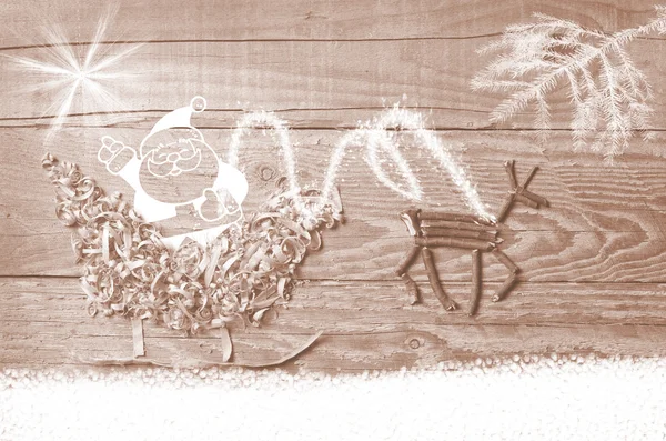 Простые символы саней Деда Мороза устроены из опилок и оленей, сделанных из сухих деревянных палочек на деревянном сером фоне. Санта Клаус в ней указывает на яркую звезду . — стоковое фото
