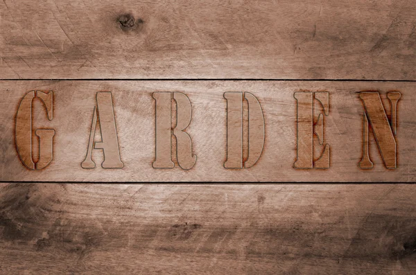 Word garden written, burned letters on wooden brown background — Stock Photo, Image