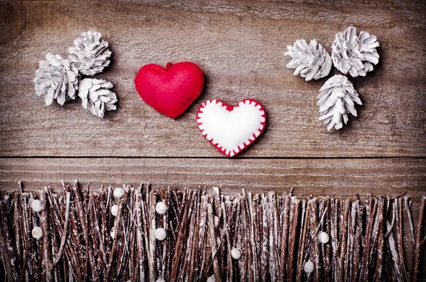 Handmade from felt hearts on wooden background. Craft arranged from sticks, twigs, driftwood and pine cones white and shiny. — Stock Photo, Image