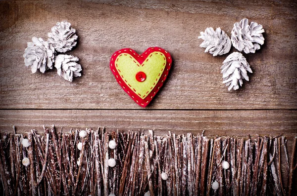 Handmade from felt heart on wooden background. Craft arranged from sticks, twigs, driftwood and pine cones white and shiny. — Stock Photo, Image