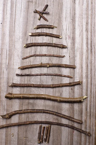 Vánoční strom uspořádány z hole, větvičky, naplavené dříví na dřevěných šedé pozadí. — Stock fotografie