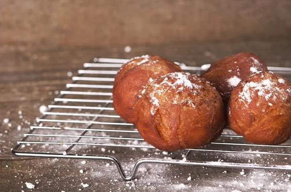 Вкусные свежеиспеченные пончики, посыпанные сахарной пудрой на вешалку на кухне . — стоковое фото