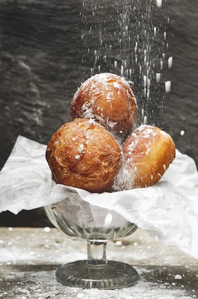 Вкусные свежеиспеченные пончики, посыпанные сахарной пудрой на кусок хлебобулочной бумаги в сахарной чашке . — стоковое фото