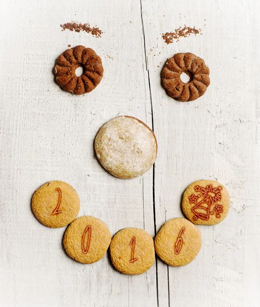 Fecha 2016 escrito en galletas dispuestas de cara divertida de la galleta — Foto de Stock
