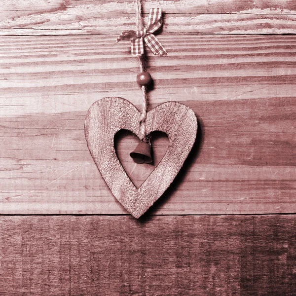 Wooden heart with bell decoration on vintage oak background, space for your text. Stock Picture